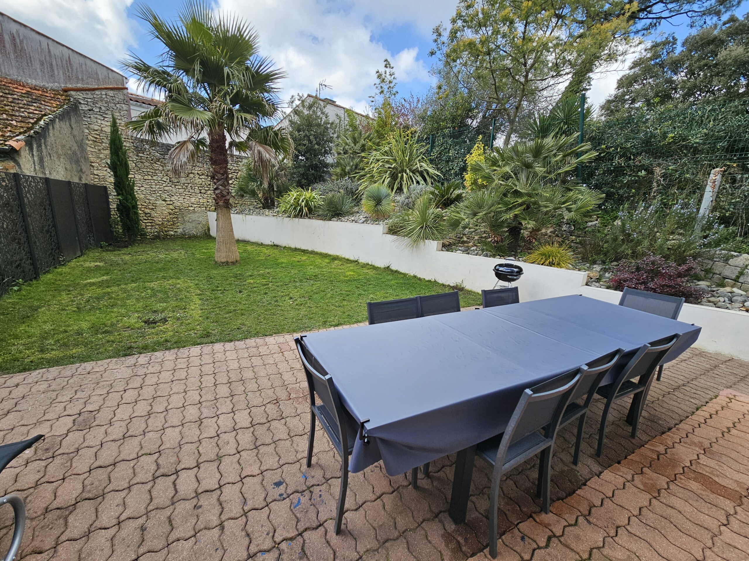 La maison offre une grande terrasse avec table à manger et barbecue Weber.